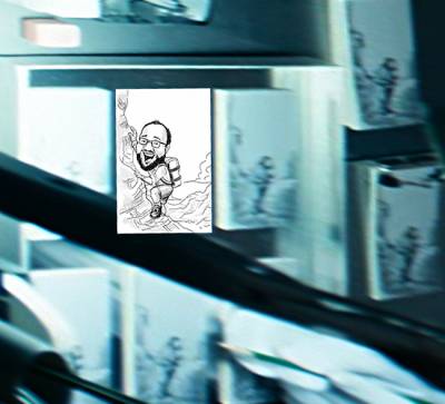 Overhead view of desk where Felicia is drawing multiple copies of the mountaineer caricature. Perspective adjusted and completed caricature added for comparison.